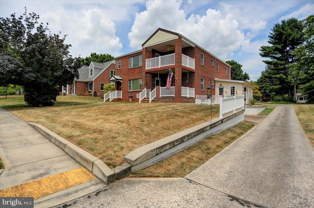 view of front facade featuring a balcony and a front lawn