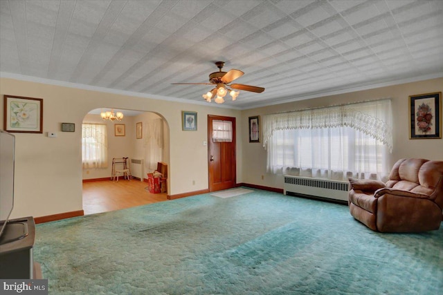 living room featuring ceiling fan with notable chandelier, ornamental molding, light carpet, and radiator