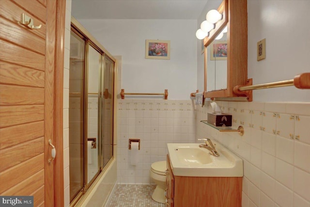 full bathroom with tile patterned flooring, combined bath / shower with glass door, toilet, vanity, and tile walls