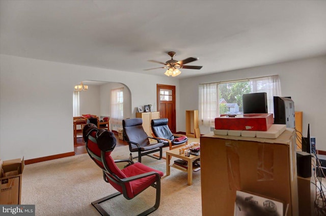 living room featuring light carpet and ceiling fan with notable chandelier