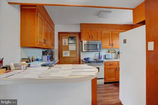 kitchen with kitchen peninsula, dark hardwood / wood-style flooring, and white appliances