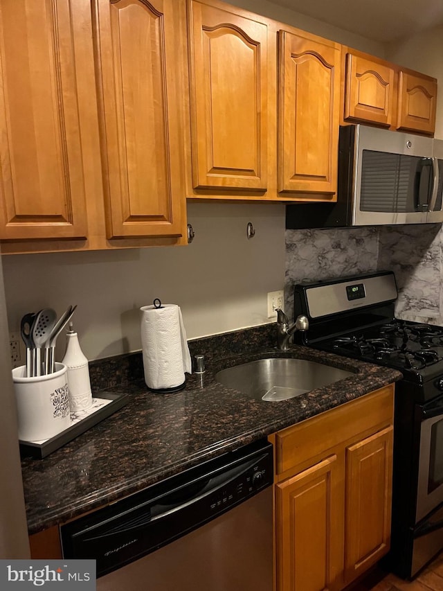 kitchen with tasteful backsplash, dark stone countertops, sink, and stainless steel appliances