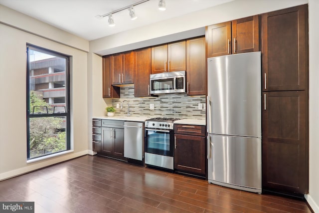 kitchen featuring sink, backsplash, appliances with stainless steel finishes, and dark wood-type flooring