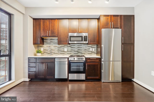 kitchen with dark hardwood / wood-style floors, stainless steel appliances, tasteful backsplash, and sink