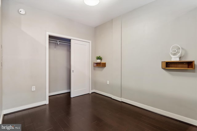 unfurnished bedroom with dark hardwood / wood-style floors and a closet