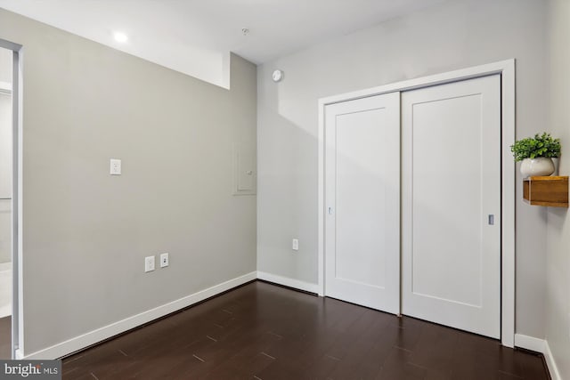 unfurnished bedroom with dark wood-type flooring and a closet