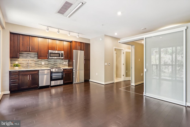 kitchen featuring appliances with stainless steel finishes, backsplash, dark wood-type flooring, and sink