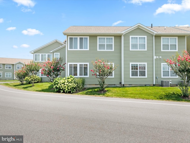 view of front of house featuring a front lawn and central AC