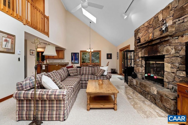 living room with rail lighting, high vaulted ceiling, light colored carpet, a fireplace, and ceiling fan with notable chandelier