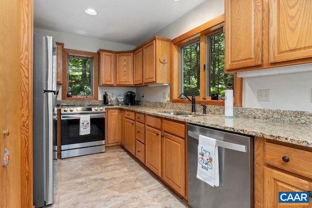 kitchen featuring light stone counters, sink, and stainless steel appliances