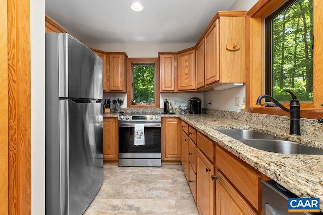 kitchen featuring light stone countertops, appliances with stainless steel finishes, and sink