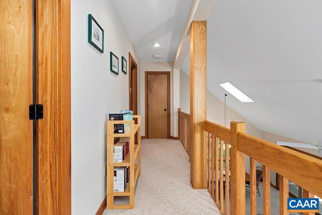 hallway featuring vaulted ceiling with skylight and light carpet