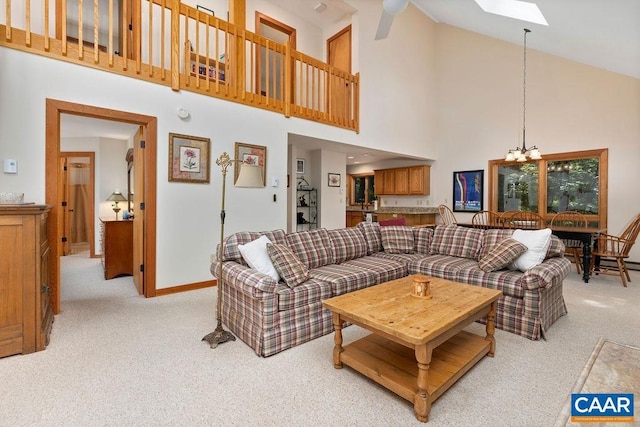 carpeted living room featuring a skylight, high vaulted ceiling, and a chandelier