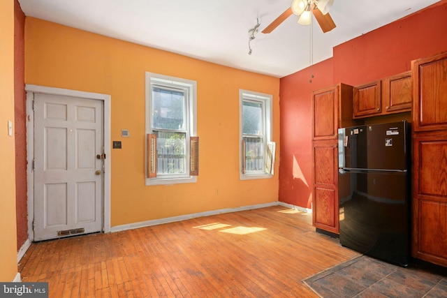 kitchen featuring ceiling fan, hardwood / wood-style floors, and black fridge