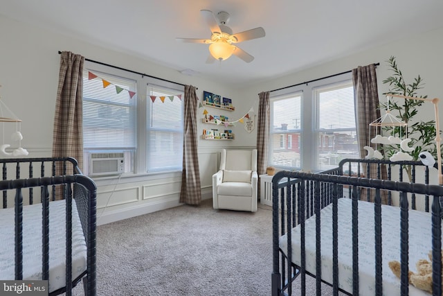 bedroom with cooling unit, ceiling fan, carpet floors, and a nursery area