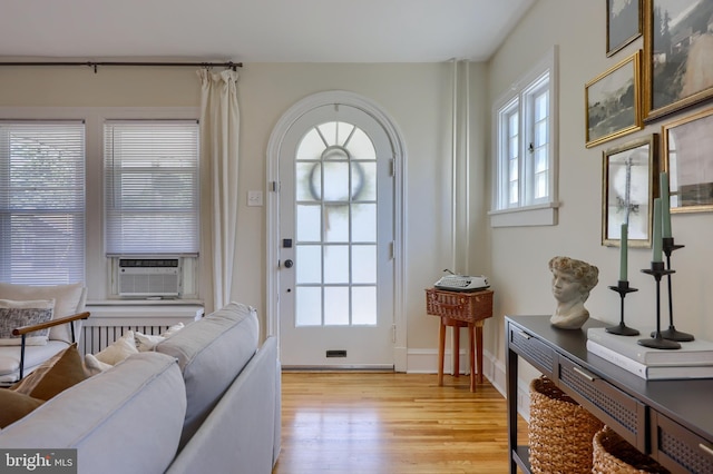 doorway to outside with radiator heating unit, cooling unit, and light hardwood / wood-style floors