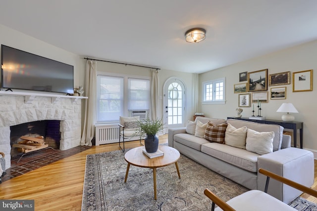 living room featuring a fireplace, wood-type flooring, and radiator heating unit