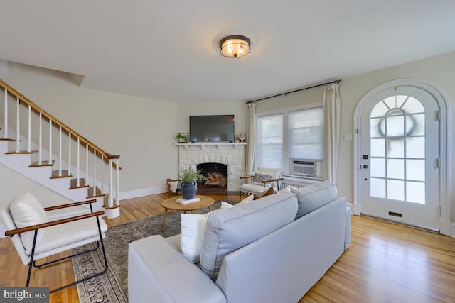 living room with light wood-type flooring, a stone fireplace, and cooling unit