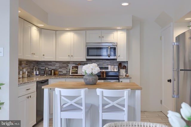 kitchen with tasteful backsplash, butcher block counters, white cabinetry, and stainless steel appliances