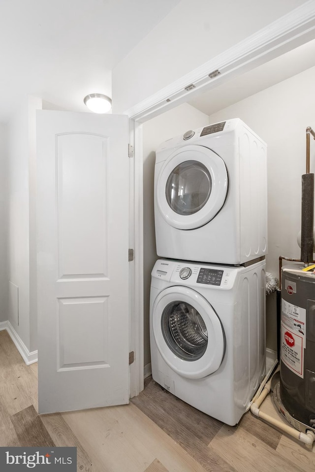 laundry room with electric water heater, light hardwood / wood-style flooring, and stacked washing maching and dryer