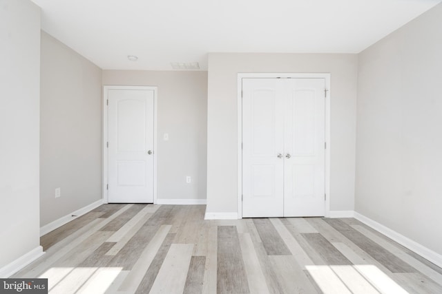 unfurnished bedroom with a closet and light wood-type flooring