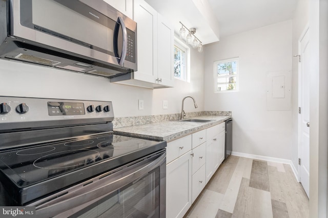 kitchen featuring sink, white cabinets, light wood-type flooring, and appliances with stainless steel finishes