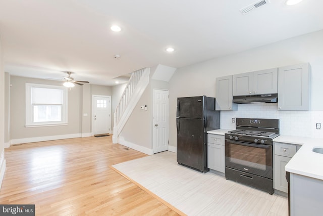 kitchen featuring light hardwood / wood-style flooring, decorative backsplash, black appliances, ceiling fan, and gray cabinets