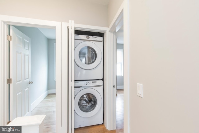 washroom featuring light hardwood / wood-style flooring and stacked washer and dryer