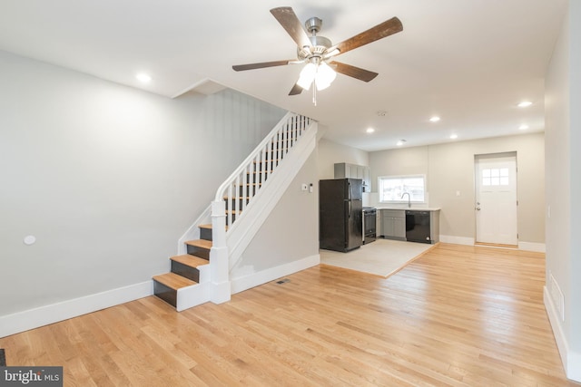 unfurnished living room featuring light wood-type flooring, sink, and ceiling fan