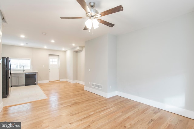 unfurnished living room featuring light tile patterned flooring, sink, and ceiling fan