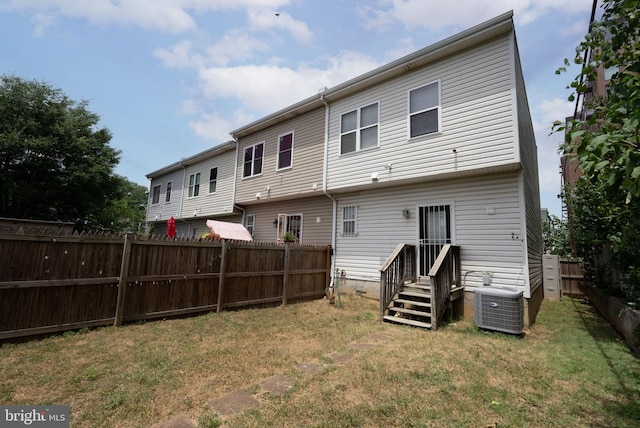 rear view of property with a yard and central air condition unit