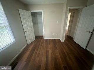 unfurnished bedroom with a closet and dark wood-type flooring