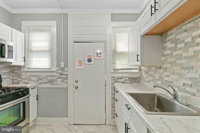 kitchen with appliances with stainless steel finishes, white cabinetry, crown molding, and sink