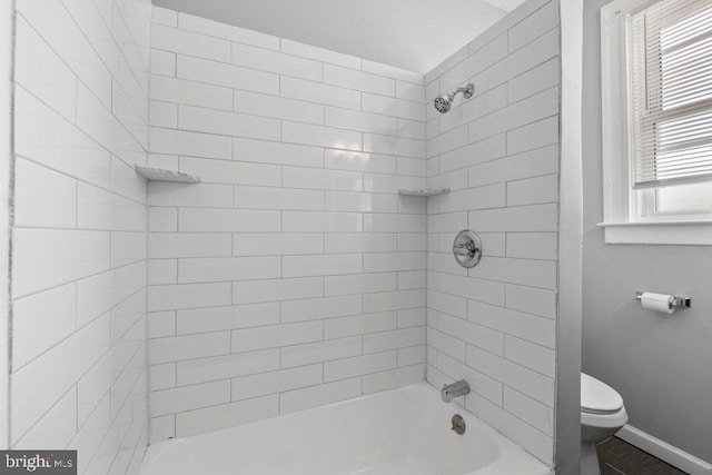 bathroom featuring a wealth of natural light, tiled shower / bath combo, and toilet