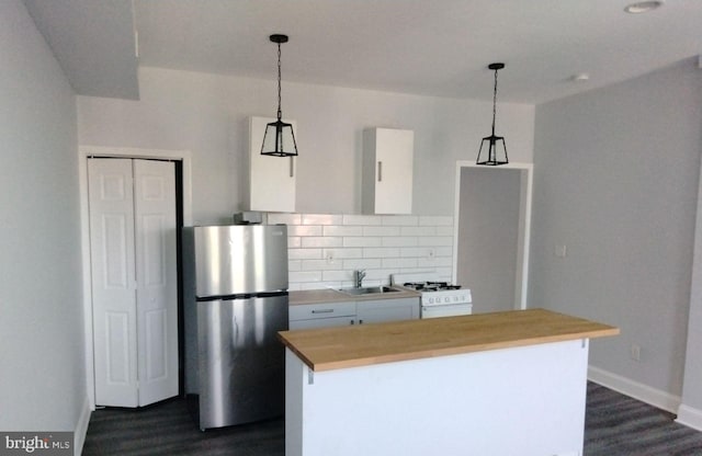 kitchen with pendant lighting, backsplash, white gas range oven, and stainless steel refrigerator