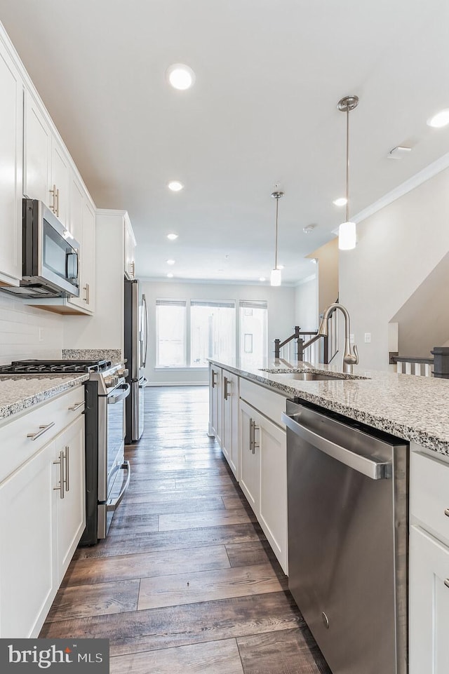 kitchen with sink, appliances with stainless steel finishes, light stone counters, white cabinets, and decorative light fixtures