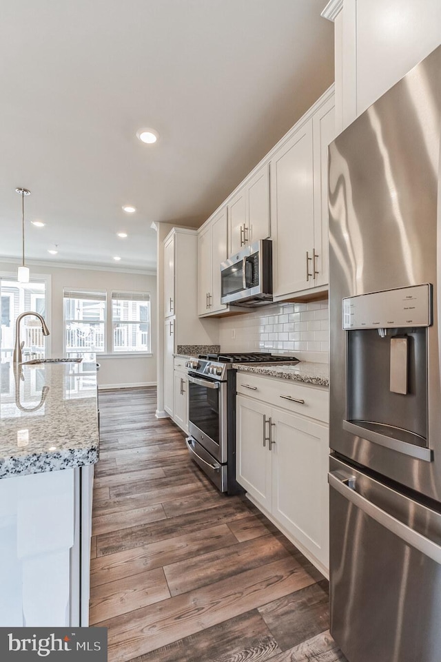 kitchen featuring stainless steel appliances, white cabinetry, pendant lighting, and light stone counters