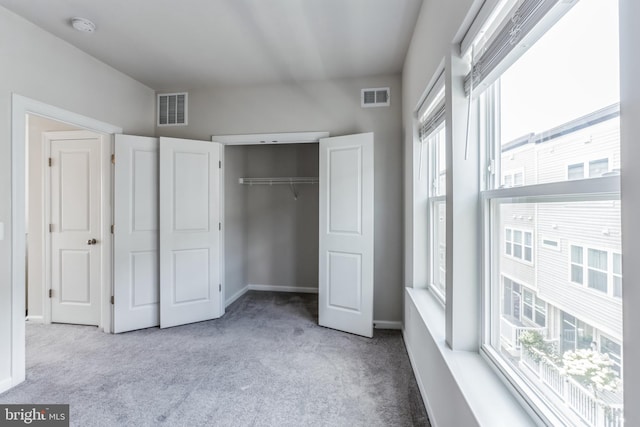 unfurnished bedroom featuring light colored carpet and a closet