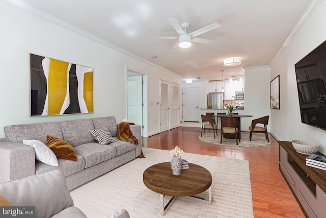 living room with wood-type flooring, crown molding, and ceiling fan