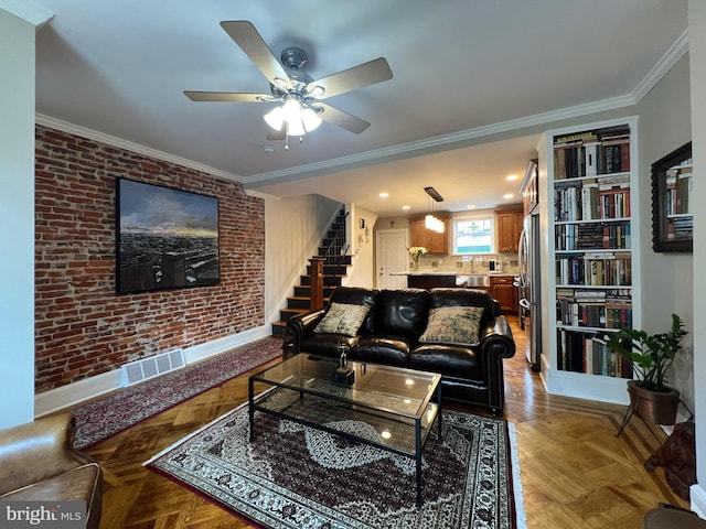 living room with ornamental molding, baseboards, stairway, and brick wall