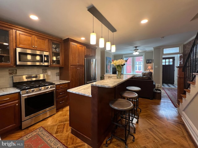 kitchen featuring glass insert cabinets, appliances with stainless steel finishes, a kitchen breakfast bar, a center island, and pendant lighting