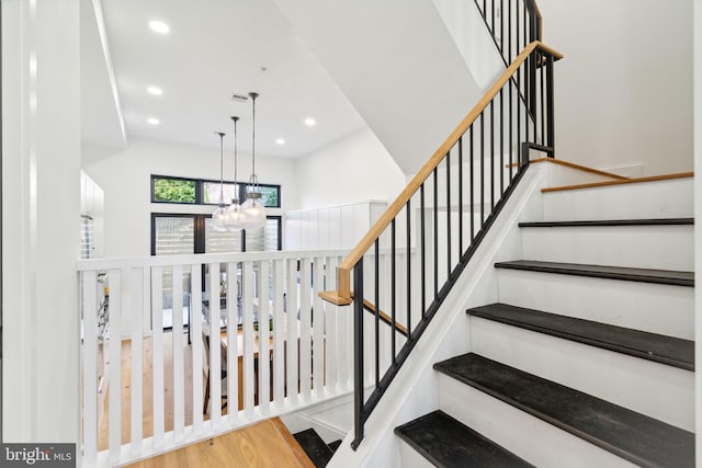 stairs featuring wood-type flooring and a chandelier