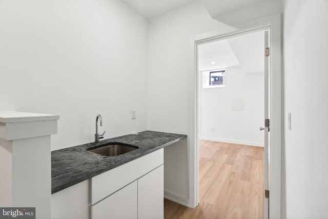 kitchen featuring sink, white cabinets, and light wood-type flooring