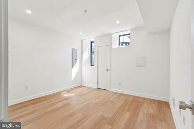 unfurnished bedroom with a raised ceiling, light wood-type flooring, and multiple closets