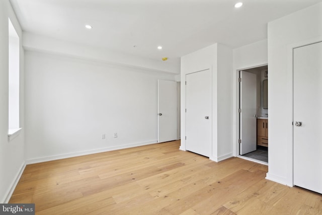 unfurnished bedroom with connected bathroom and light hardwood / wood-style floors