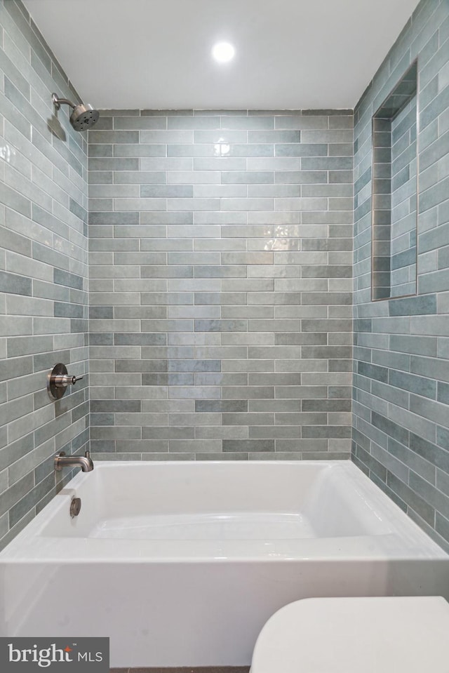 bathroom with toilet and tiled shower / bath combo