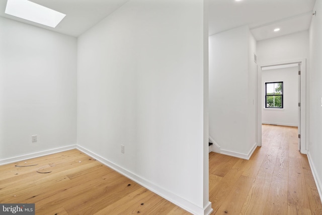 hall featuring a skylight and light hardwood / wood-style flooring