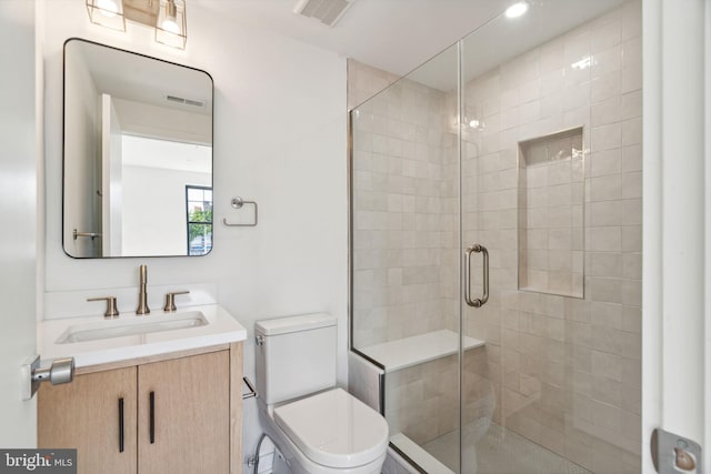 bathroom featuring vanity, toilet, and a shower with shower door