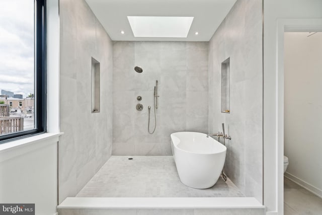 bathroom featuring tile walls, toilet, tile patterned floors, a skylight, and independent shower and bath