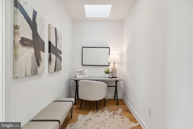 office area with light hardwood / wood-style floors and a skylight